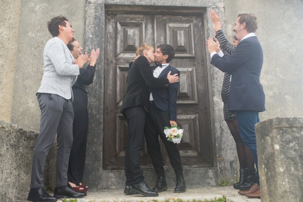 Two gay men getting married and kissing in view of their friends and family. Open relationships include same sex couples who are married.